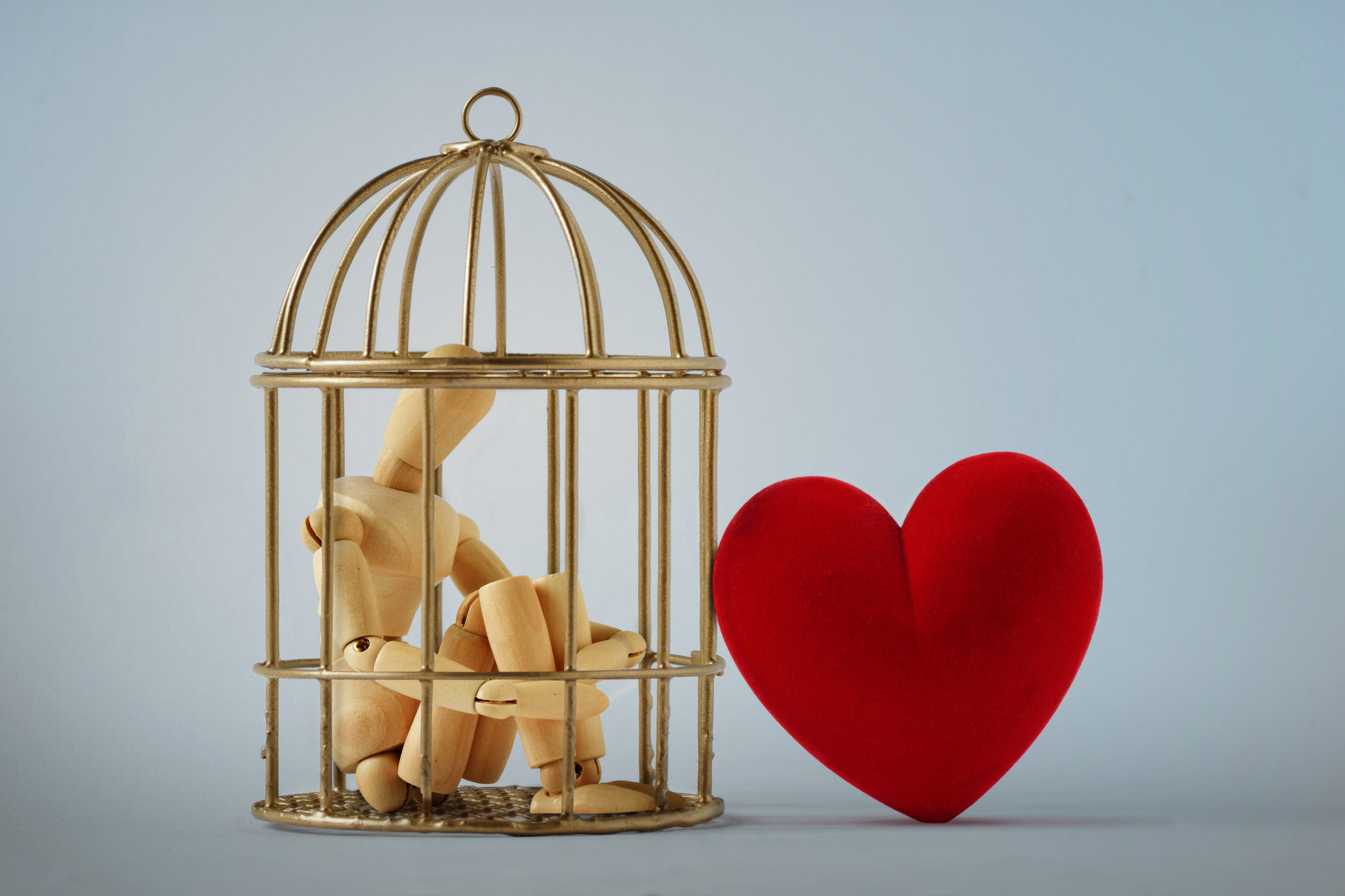 Wooden mannequin in a bird cage and free heart - Love and freedom concept Wooden mannequin in a bird cage and free heart - Love and freedom concept