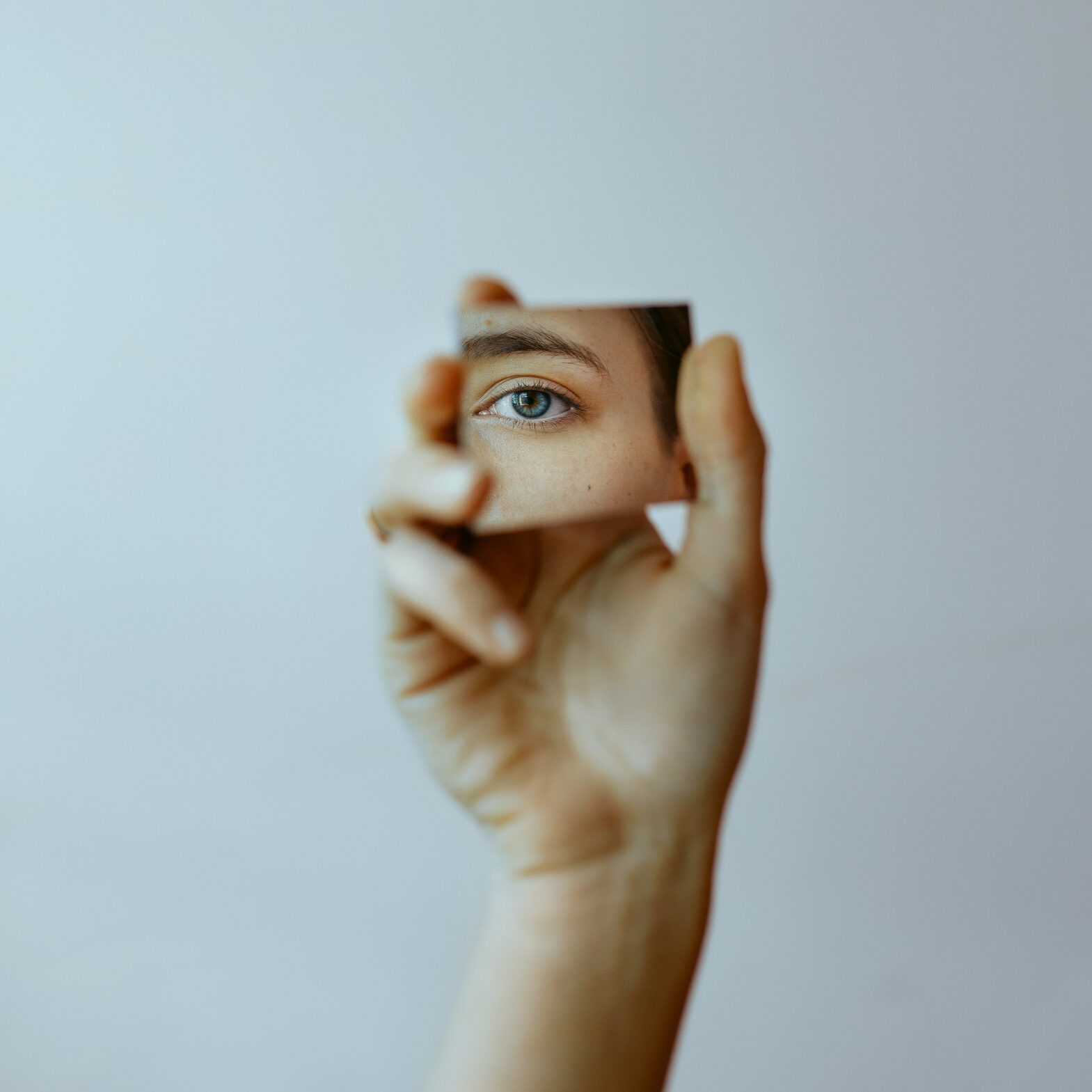 Cropped hand holding mirror with reflection of eye Cropped hand holding mirror with reflection of eye